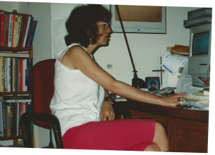Woman sitting at desk, surrounded by books.
