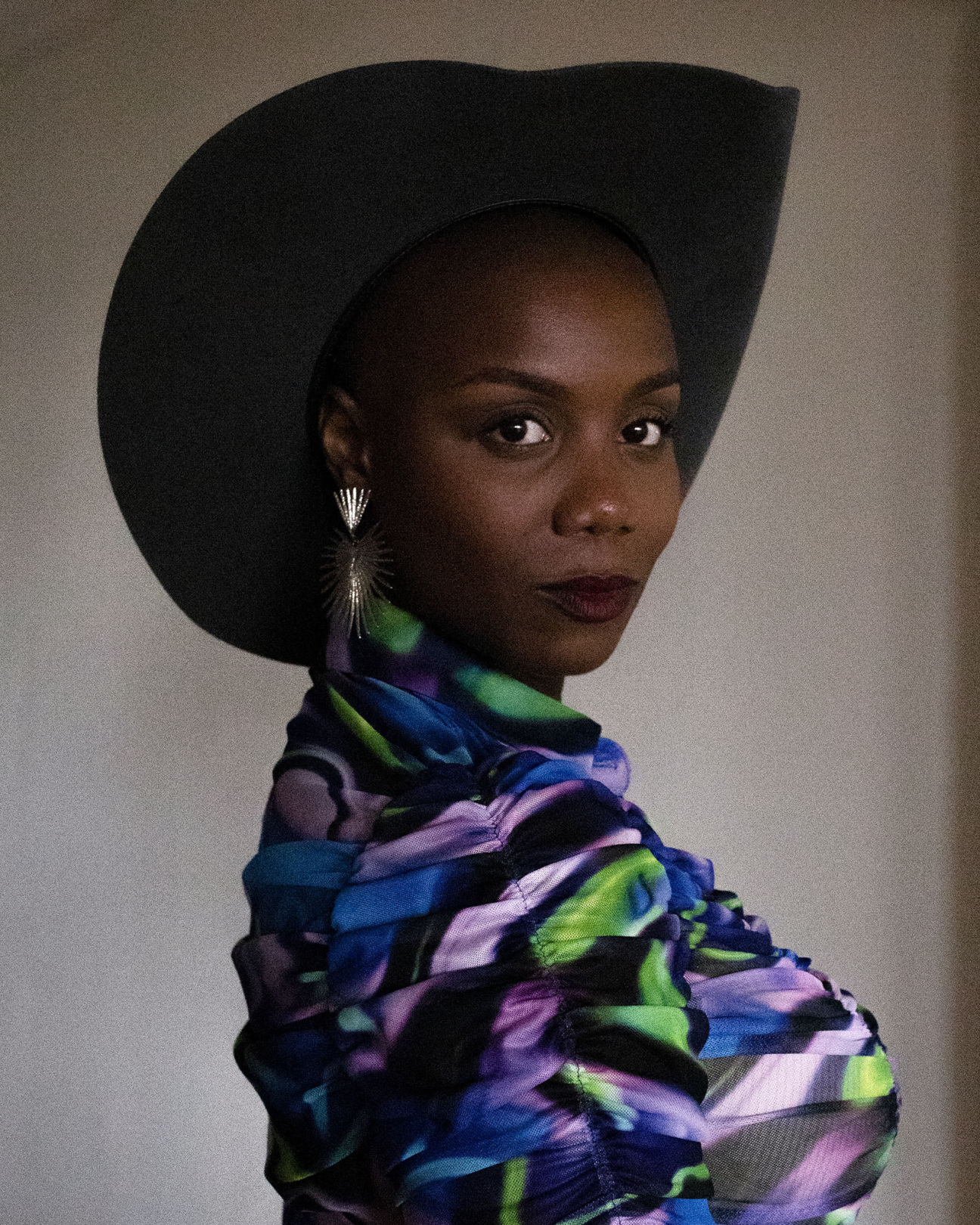 Woman wearing white puffer coat stands against a white wall with pink textures being projected on top of her face.